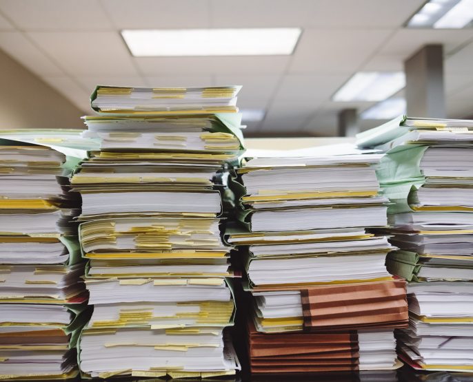 four large stacks of reports documents in office environment