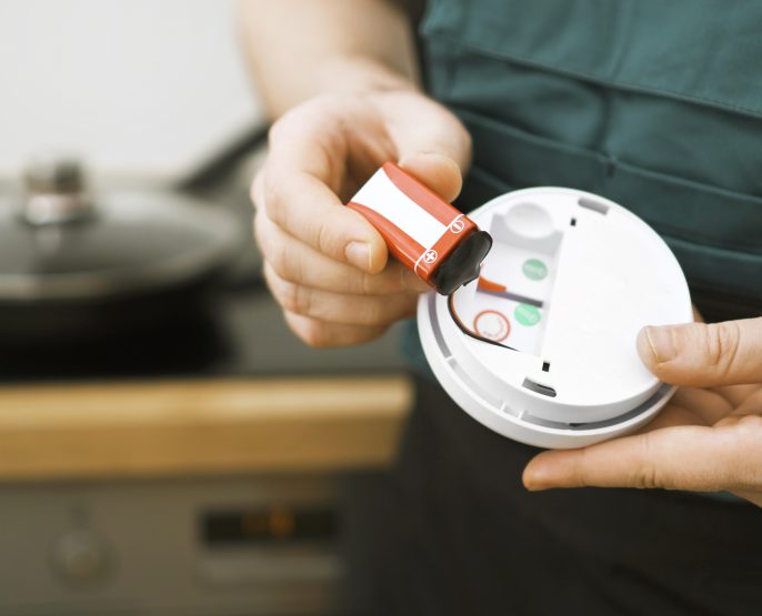 Man checking battery in smoke detector in the kitchen