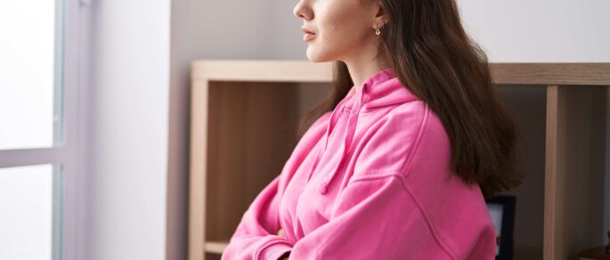Silhouette of young woman experiencing family violence holding a young child against sunset background