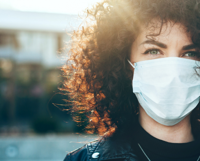 dark curly haired woman in leather jacket in COVID-19 wearing a mask