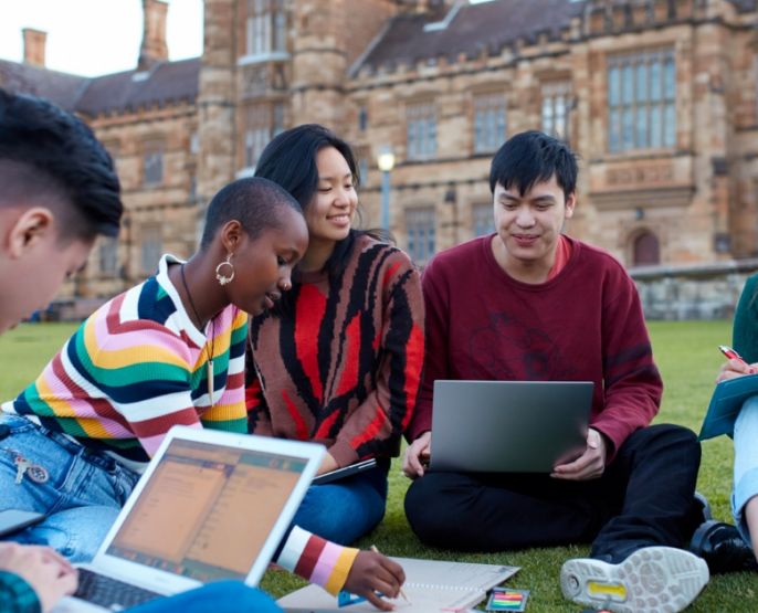 five multicultural international students studying on a lawn in front of a university building